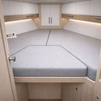A U-shaped upholstered seating or sleeping berth area with light gray cushioned seats set into a wood-and-white cabin interior.