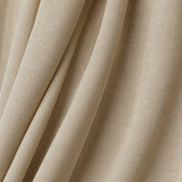 A close-up of draped beige fabric with soft folds and a subtle woven texture.