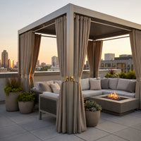 Taupe Sunbrella outdoor curtains with gold grommet tiebacks on a modern rooftop lounge pergola with fire pit and city skyline at sunset