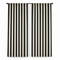 Black and off-white striped curtain panels hanging on a black rod in a bright room with a window, side table, and framed wall art.