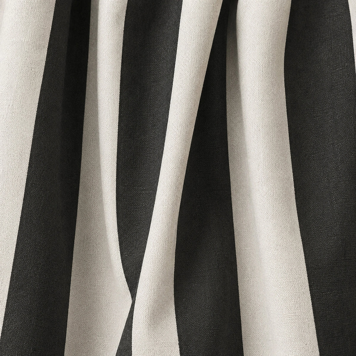 A close-up of draped fabric with bold vertical black and off-white stripes, showing the material texture and folds.