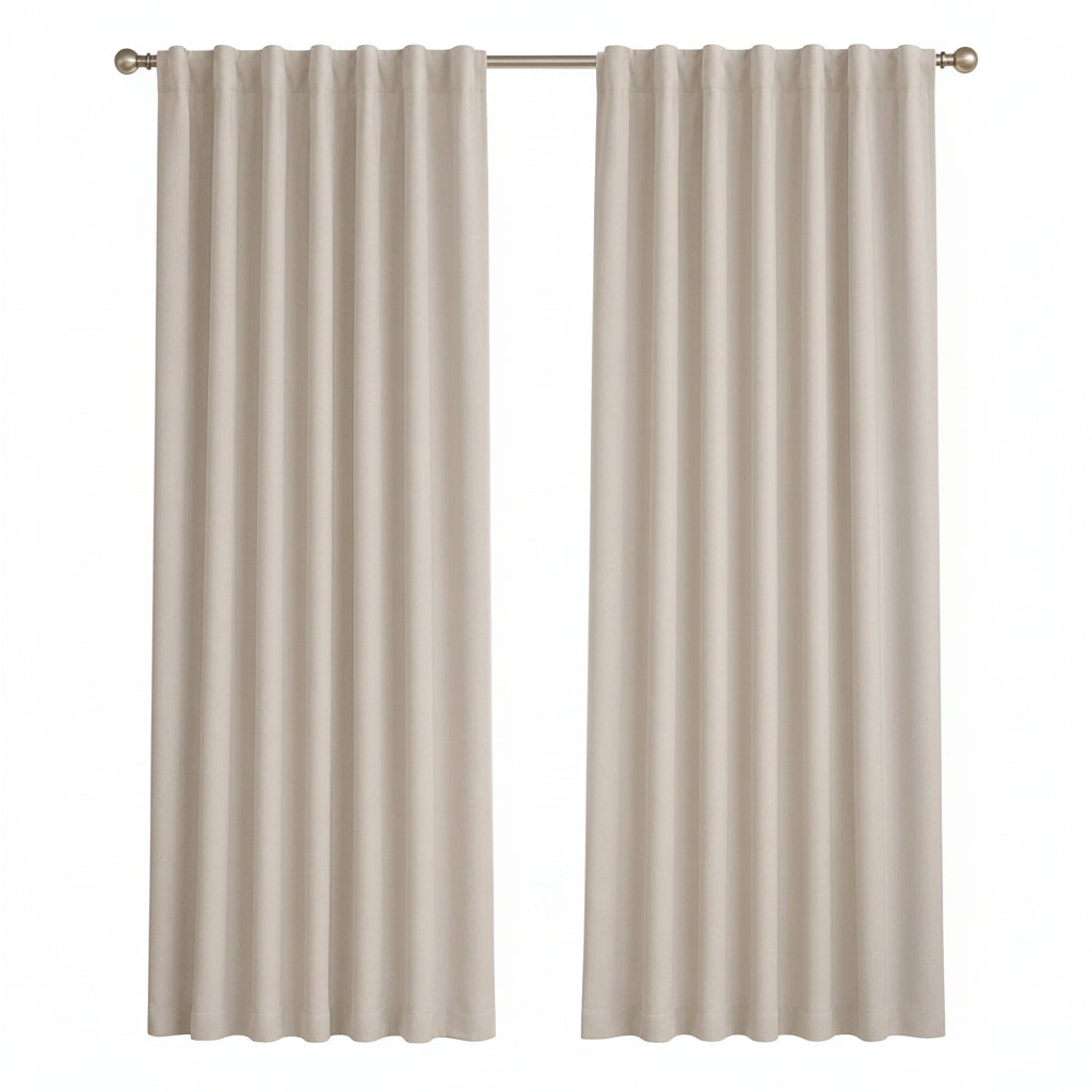 A pair of light beige curtain panels hanging on a silver rod in a bright, modern room with a window, a small wooden side table with a vase, and a light-colored armchair.