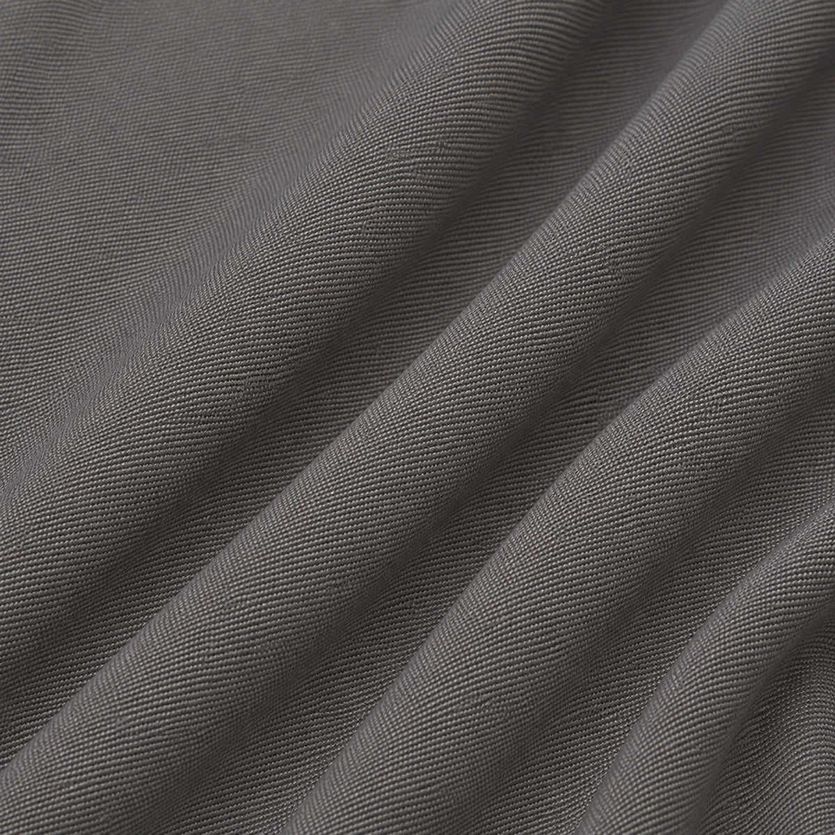 A close-up of dark gray woven fabric with soft diagonal folds showing the textile texture.