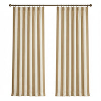 A pair of floor-length curtain panels with vertical stripes in beige and off-white, hanging from a dark metal rod in a bright room with a window, wood cabinet, and framed wall art.