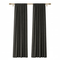 A pair of dark charcoal gray curtain panels hanging from a gold curtain rod against a plain beige wall.